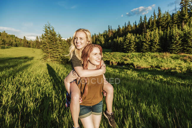 Happy friends having fun in park with piggyback ride — Stock Photo