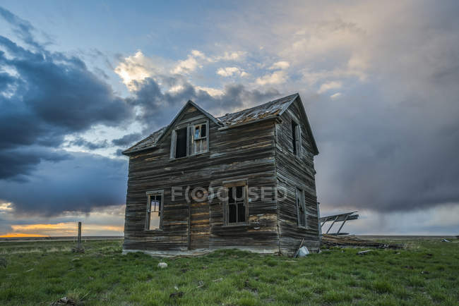 Casa abandonada nas pradarias com nuvens de tempestade ao pôr-do-sol; Val Marie, Saskatchewan, Canadá — Fotografia de Stock