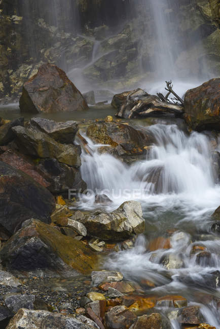 Sfocatura di movimento di una cascata che schizza in una piscina e cade su rocce; Alaska, Stati Uniti d'America — Foto stock