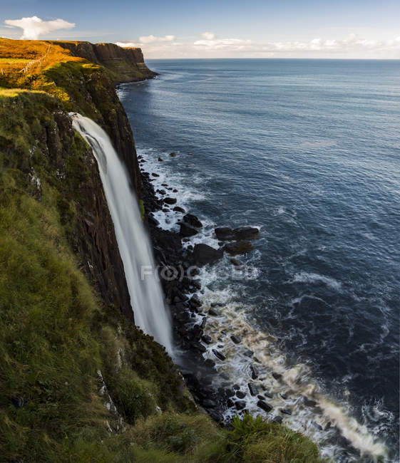 A waterfall flowing over a cliff along the coastline; Isle of Skye, Scotland — Stock Photo