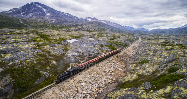 Um trem atravessa a paisagem estéril a caminho de Carcross; Yukon Territory, Canadá — Fotografia de Stock