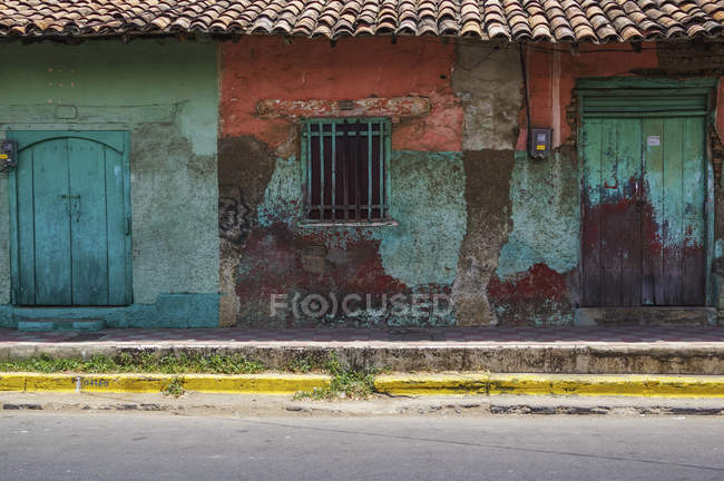Abgenutzte und verwitterte Fassade eines Gebäudes mit abblätternder Farbe und Doppeltüren; nicaragua — Stockfoto