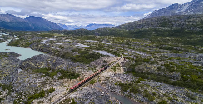 A train runs through the barren landscape on its way to Carcross; Yukon Territory, Canada — Stock Photo
