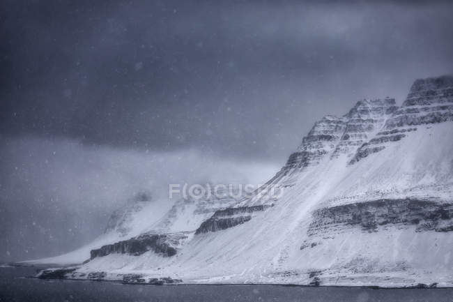 Una tormenta de nieve a lo largo de la costa de Strandir en los fiordos occidentales de Islandia; Islandia - foto de stock