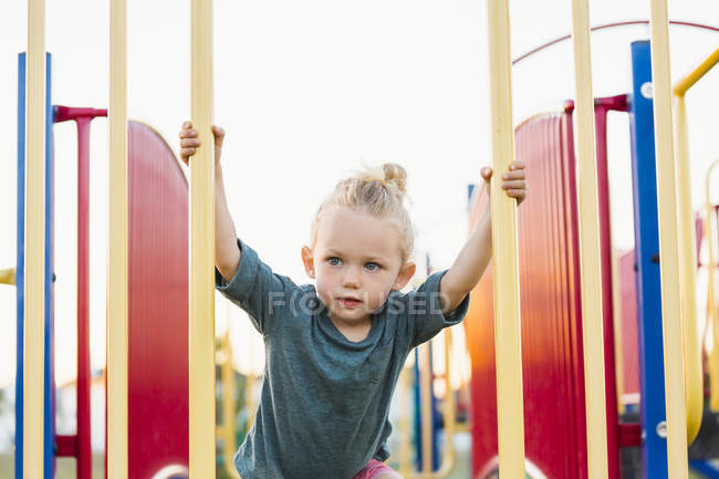 Young girl playing in playground and climbing rock ladder — Stock Photo