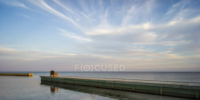 Wooden bench at the end of a dock facing the open ocean at sunrise, Belize — Stock Photo