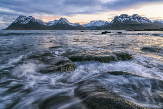 Sunset over the mountains of the Strandir Coast, Iceland as the surf pounds the shoreline; West Fjords, Iceland — Stock Photo