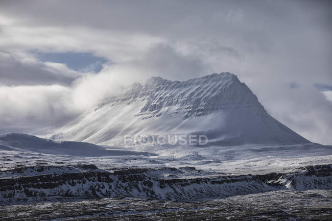 Neve coberto pico atrás da cidade de Djupavik; Djupavik, West Fjords, Islândia — Fotografia de Stock