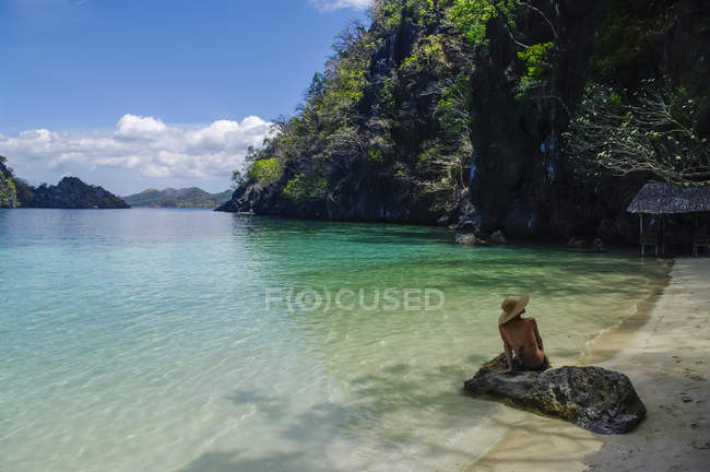 Femme en bikini assise sur un rocher le long d'une côte tropicale, Andaman, Inde — Photo de stock