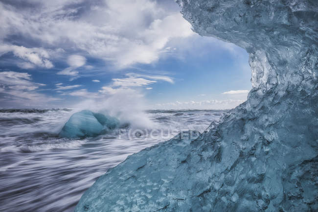 Hielo azul y témpanos con salpicaduras de agua en Jokulsarlon, costa sur; Islandia - foto de stock