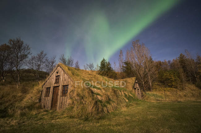 Aurora boreale su una casa di zolle lungo la costa meridionale dell'Islanda; Islanda — Foto stock