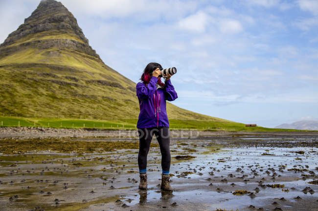 Escursionista donna che scatta foto con macchina fotografica davanti al Kirkjufell Mountain, Islanda — Foto stock