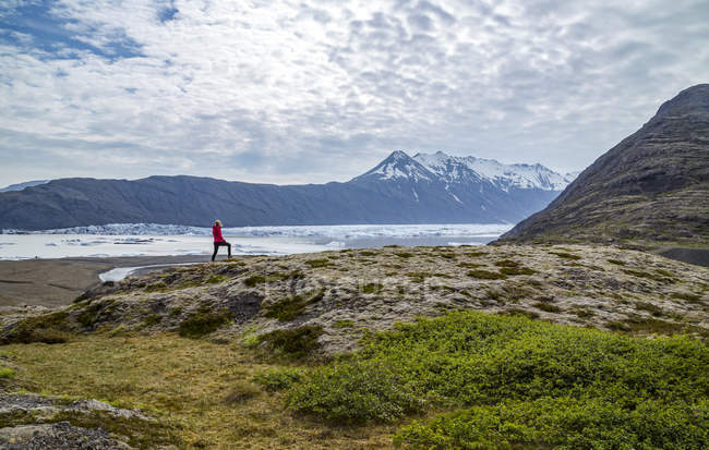 Excursionista femenina de pie en el lago glaciar, Parque Nacional Vatnajokull, Islandia - foto de stock