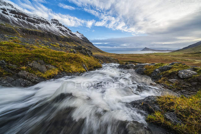 Fluss, der an der fremdartigen Küste, Westfjorden, zum Ozean fließt; Island — Stockfoto