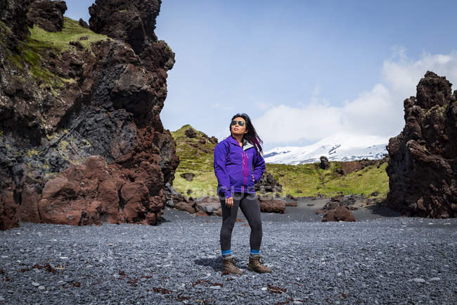 Turista asiatica sulla spiaggia di sabbia nera vicino a una formazione rocciosa, penisola di Snaefellsnes, Islanda — Foto stock