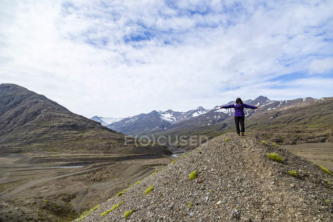 Жіночий мандрівного з обіймами розкритими на вершині пагорба в горах, Ісландія — стокове фото
