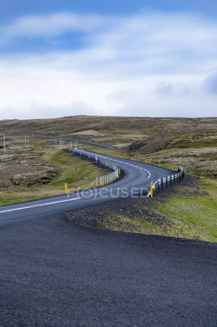 Strada vuota si snoda attraverso le aspre colline paesaggistiche, Islanda — Foto stock