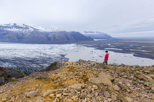 Excursionista femenina de pie en el lago glaciar, Parque Nacional Vatnajokull, Islandia - foto de stock