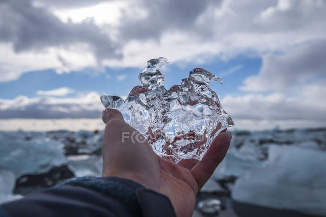 Imagem recortada do homem segurando um pedaço de gelo em Jokulsarlon, Islândia — Fotografia de Stock