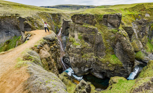 Turista femenina parada en un mirador de acantilado en el pintoresco valle de Fjadrargljufur, Islandia - foto de stock