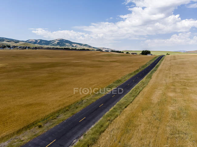 Gerade Straße durch die Landschaft mit goldenen Feldern von Ackerland auf beiden Seiten, mendon, utah, usa — Stockfoto