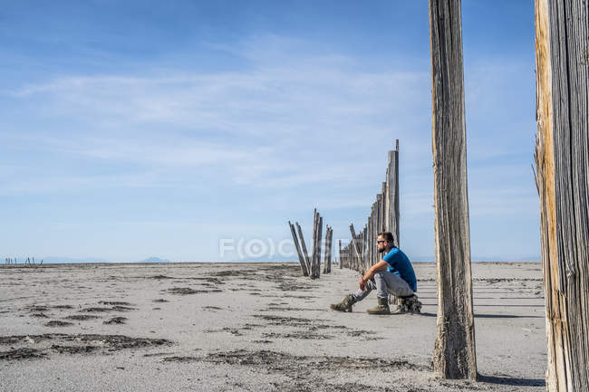 Mann sitzt auf einem Baumstumpf auf einer kargen Weite des Landes, großer Salzsee, utah, usa — Stockfoto