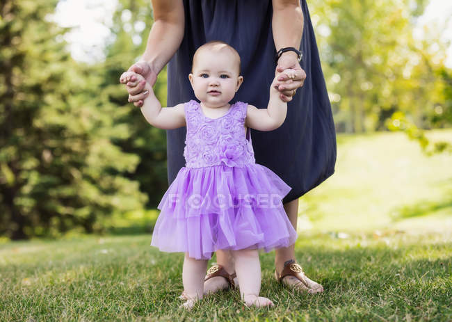 Mother teaching her baby daughter how to walk — Stock Photo