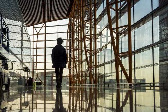 Passenger standing in airport terminal building looking out the window, Beijing Capital International Airport, Beijing, China — Stock Photo