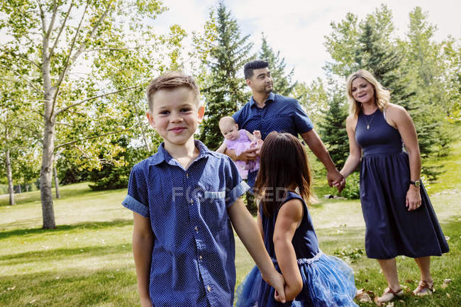 Madre y padre caminando con niños en un parque - foto de stock