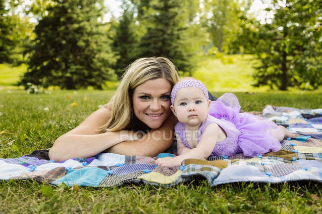 Mother and baby daughter laying on a picnic blanket — Stock Photo