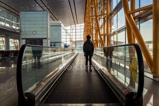 Passenger standing on moving sidewalk in airport terminal building, Beijing Capital International Airport, Beijing, China — Stock Photo