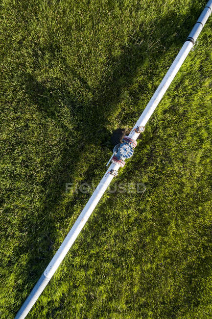 Aerial view of a pipeline with a value and coupling in a green field, West of Calgary; Alberta, Canada — Stock Photo