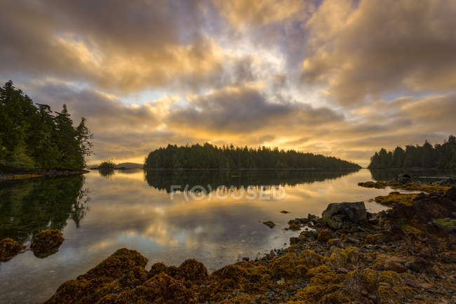 Le soleil se lève par un ciel nuageux au-dessus des îles Broken Group au large de la côte ouest de l'île de Vancouver, réserve de parc national Pacific Rim, Colombie-Britannique, Canada — Photo de stock