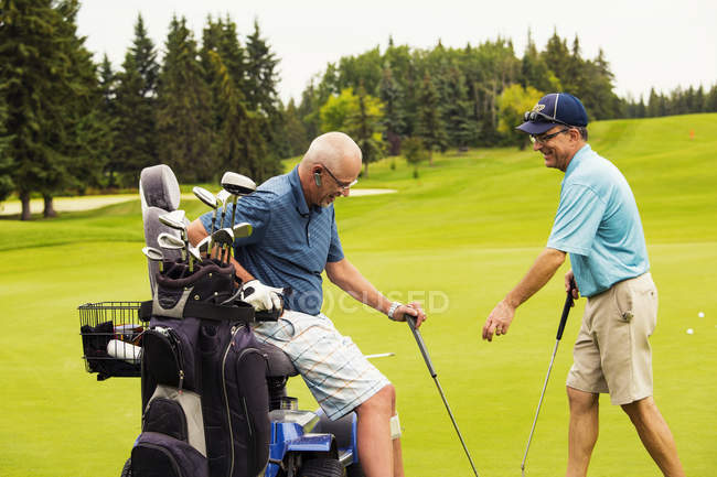 Інвалідів гольфіста за допомогою спеціалізованих візку teeing off і водіння м'яч вниз фарватер поле для гольфу, Едмонтон, Альберта, Канада — стокове фото