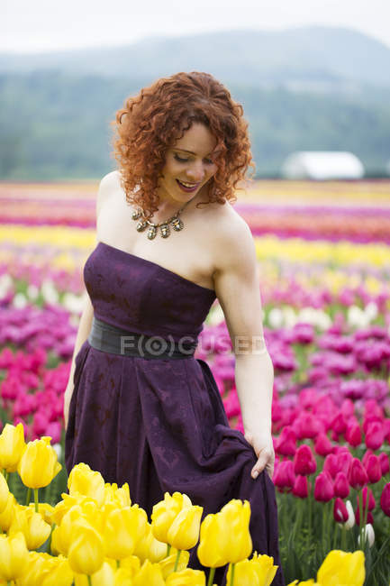 Schöne Frau mit roten Haaren steht im Feld der Tulpen — Stockfoto
