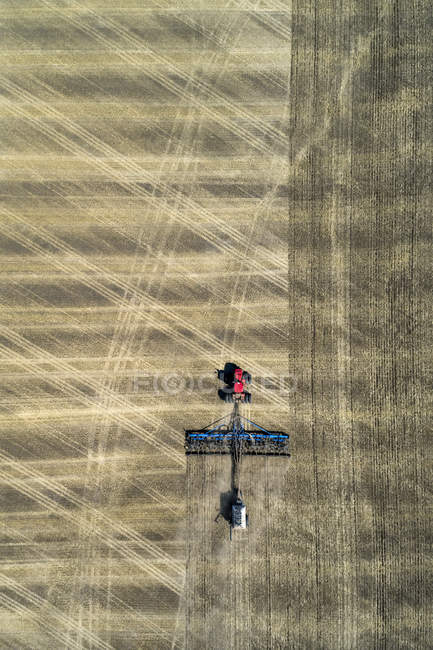 Vista aérea de un tractor tirando de una sembradora de aire, sembrando un campo - foto de stock