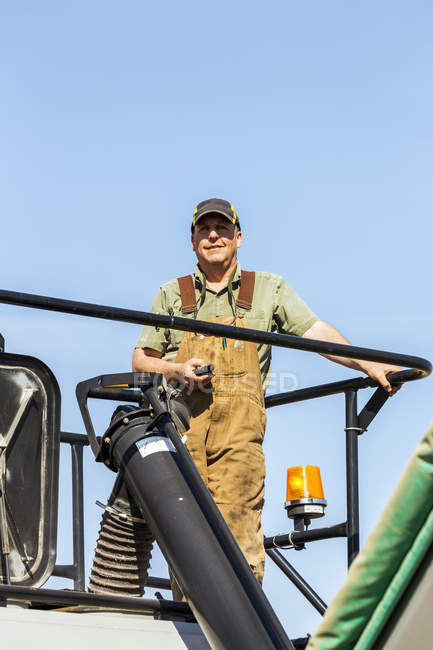 Agricultor masculino que trabaja con maquinaria pesada en el campo - foto de stock