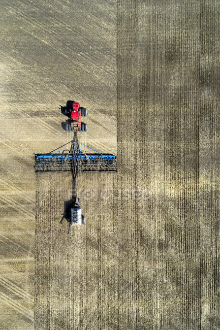 Вид с воздуха на трактор, вытаскивающий сеялку, сеющий поле — стоковое фото
