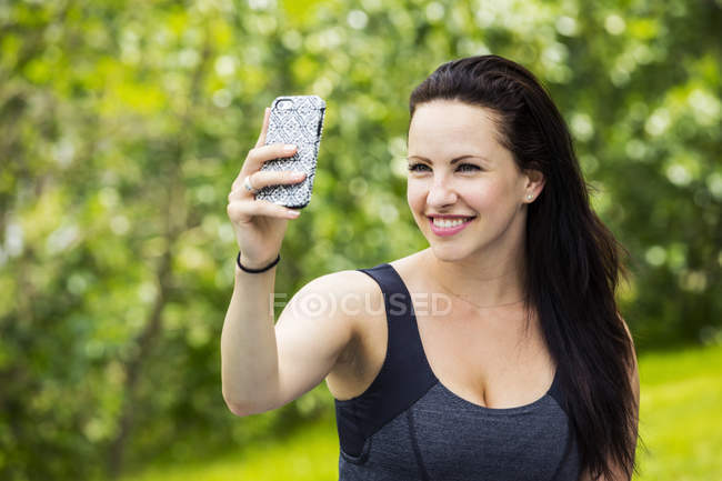 Красива молода жінка бере автопортрет, насолоджуючись на відкритому повітрі в парку — стокове фото