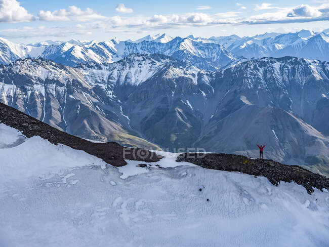 Woman standing with her arm raised while on a ridge line in Kluane National Park and Reserve; Haines Junction, Yukon, Canada — Stock Photo