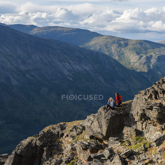 Deux femmes utilisent leur téléphone cellulaire et explorent les montagnes et la nature sauvage du Yukon autour de Haines Junction ; Yukon, Canada — Photo de stock