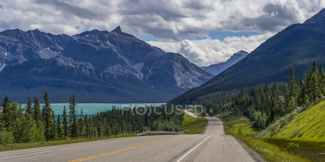 Road through the rugged Canadian Rocky Mountains with a turquoise alpine lake and forests; Clearwater County, Alberta, Canadá — Fotografia de Stock