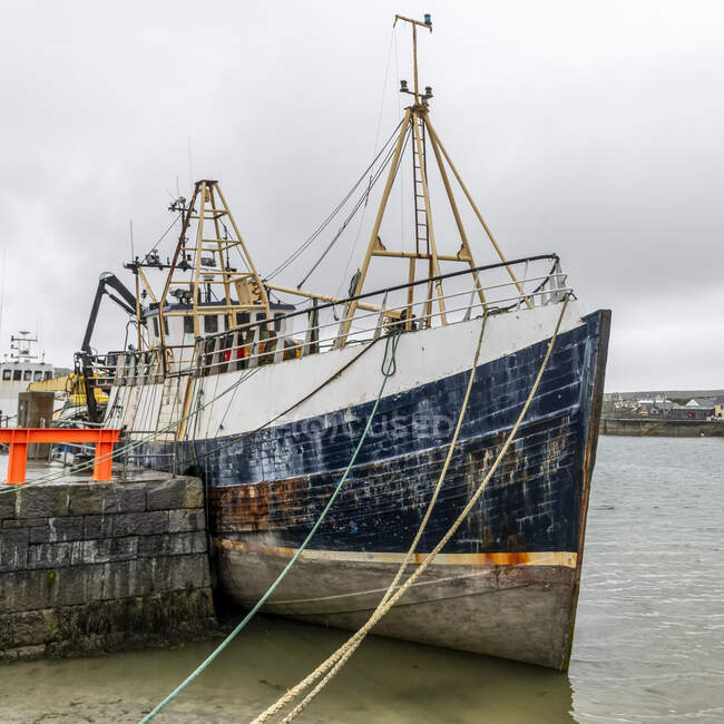 Barco amarrado en el puerto a lo largo de la costa oeste de Irlanda en la desembocadura de la bahía de Galway, Inishmore, Islas Aran; Kilronan, Condado de Galway, Irlanda - foto de stock