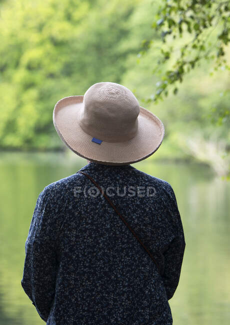 Жінка з підшитим капелюхом дивиться на спокійне озеро Нортумберленд (Англія). — стокове фото