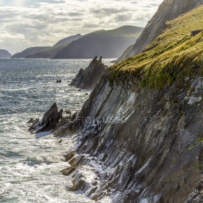 Vue panoramique sur le littoral accidenté du comté de Kerry avec des éclaboussures d'eau sur les falaises rocheuses, Ballyferriter, comté de Kerry, Irlande — Photo de stock