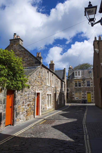 Casas con puertas de colores brillantes a lo largo de un camino tendido con setts; St Andrews, Fife, Escocia - foto de stock
