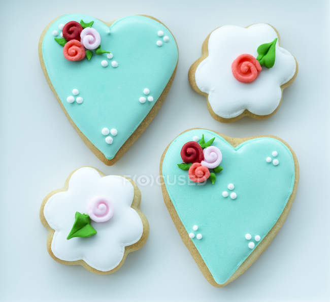 Galletas en forma de corazón y flor heladas y decoradas con flores y perlas - foto de stock