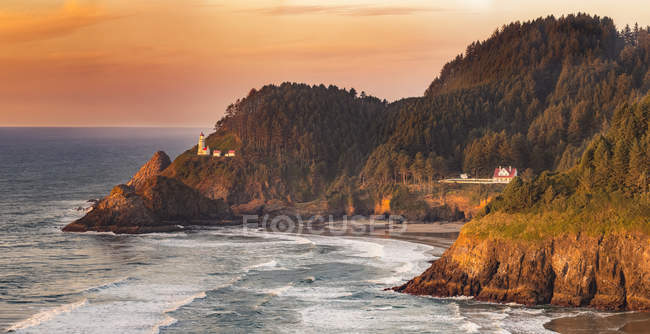 Tramonto lungo la costa dell'Oregon con formazioni rocciose sagomate e un sole dorato riflesso nelle piscine di marea sulla spiaggia di Heceta Head; Firenze, Oregon, Stati Uniti d'America — Foto stock
