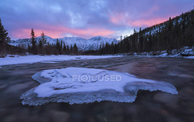 Sunrise over the mountains near Whitehorse with the Wheaton River flowing towards and clouds reflected into the river, Whitehorse, Yukon, Canada — Stock Photo