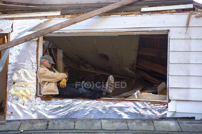Человек, спящий на рабочем месте, сидящий на краю открытого окна в ремонте; Олимпия, Вашингтон, США — стоковое фото